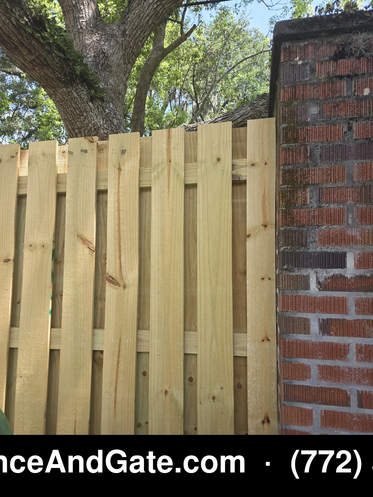 Close-up detail of pressure-treated pine shadowbox fence pickets with brick column